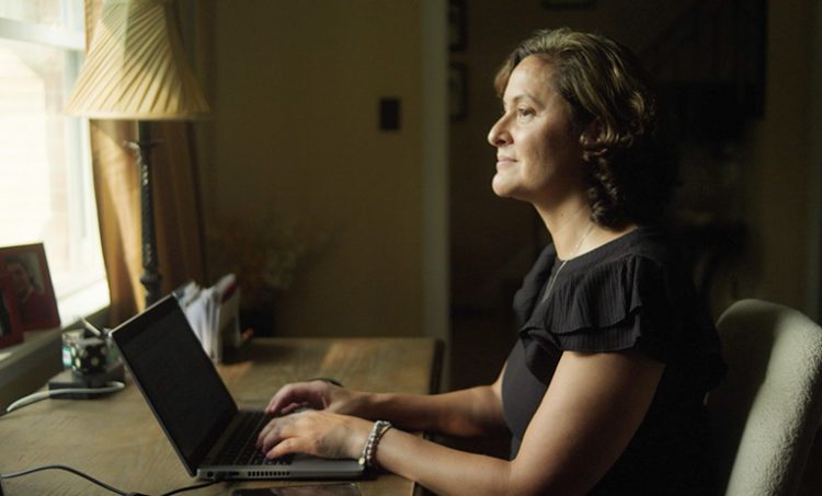 Photograph of Liv, a woman with HER2+ breast cancer, typing on a computer